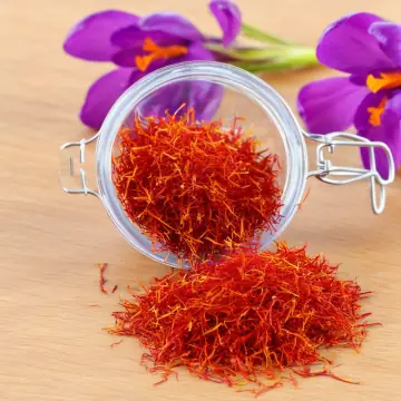Red saffron threads spilling from a glass jar, with crocus flowers