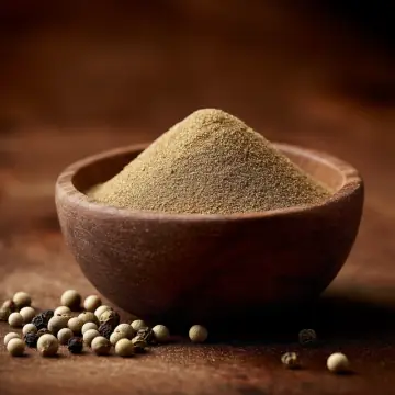 Ground white pepper in a bowl, with white peppercorns